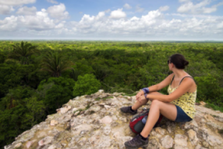 Speaker sitting on top of ruin, looking over the jungle.